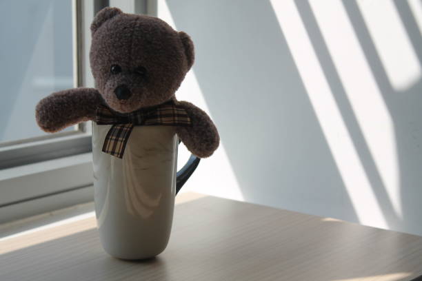 istock Bear toy in cup sitting by the window in shadows 884749866