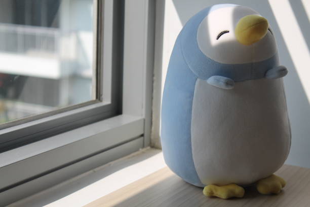 istock Penguin toy sitting by the window in shadows 884758348