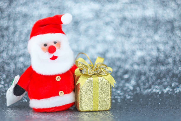 istock Santa claus doll and golden gift box with bokeh background. 884775894