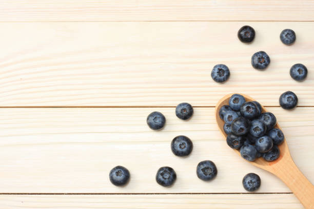 istock blueberries in wooden spoon on light wooden table background. top view with copy space 884787414