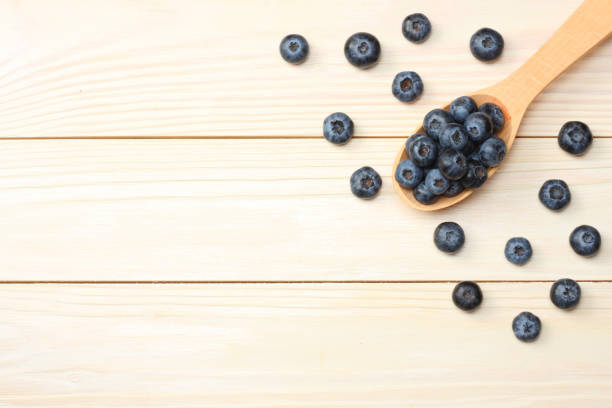 istock blueberries in wooden spoon on light wooden table background. top view with copy space 884787456