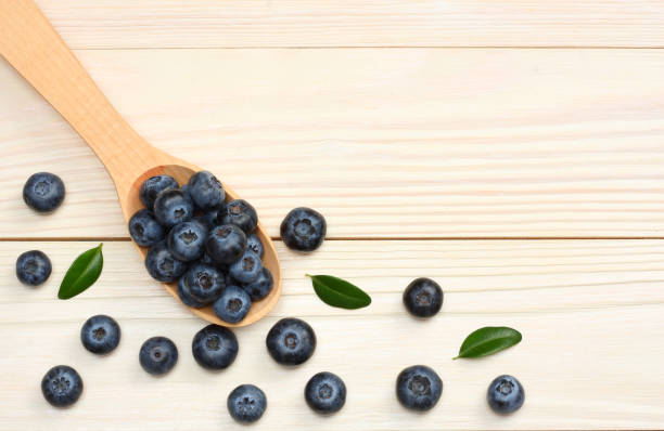 istock blueberries in wooden spoon on light wooden table background. top view with copy space 884789828