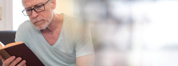 istock Portrait of mature man reading a book, light effect 884819640