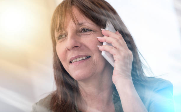 istock Mature woman calling on mobile phone, light effect 884826614