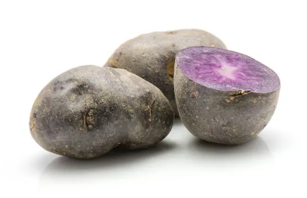 Two vitelotte potatoes and one purple half isolated on white background"n