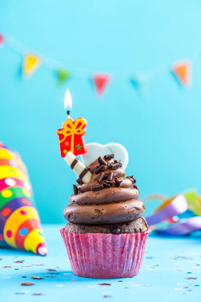 istock Colorful cupcake with single candla alight 884873180