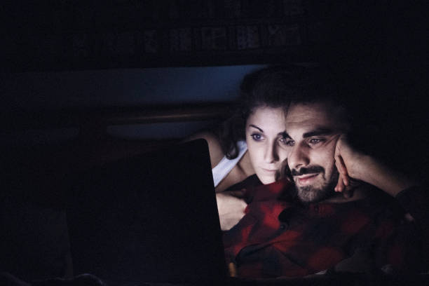 istock Young couple kissing behind a computer screen 884906496