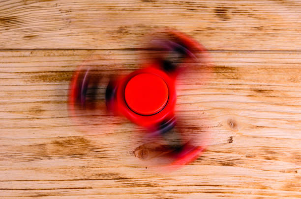 istock Red fidget spinner rotates on wooden desk 884912966