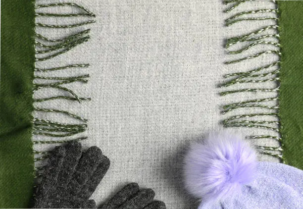 Khaki green fringe scarf, gloves and pink hat set background with empty copy space