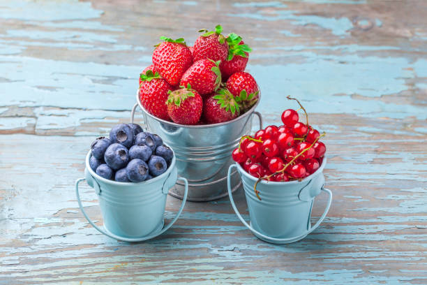 istock Berries in three blue cans on old blue wooden table 884945012