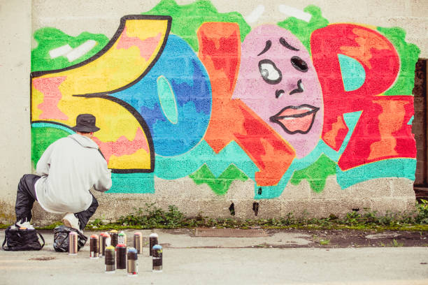 istock Young Graffiti Artist Spraying Graffiti on Wall 884972034