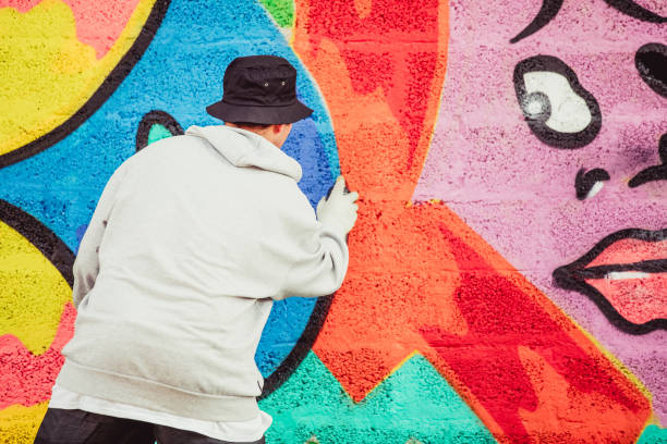istock Young Graffiti Artist Spraying Graffiti on Wall 884972040