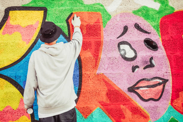 istock Young Graffiti Artist Spraying Graffiti on Wall 884972046