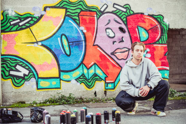 istock Young Graffiti Artist Posing in Front of His Graffiti 884972066