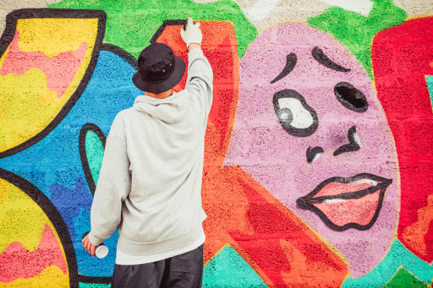 istock Young Graffiti Artist Spraying Graffiti on Wall 884972092