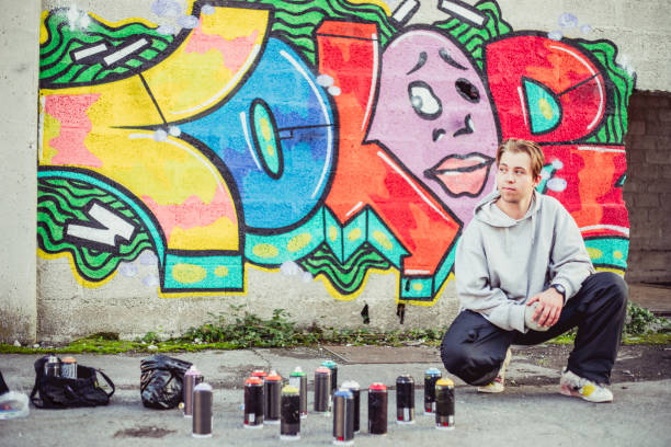 istock Young Graffiti Artist Posing in Front of His Graffiti 884972104
