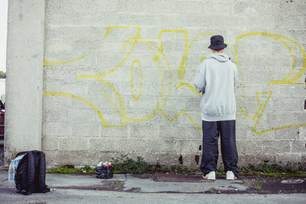 istock Young Graffiti Artist Spraying Graffiti on Wall 884972106