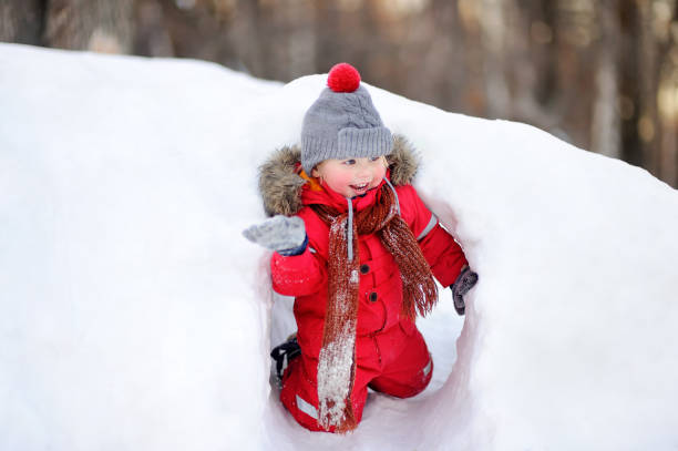 istock Little boy in red winter clothes having fun with fresh snow 885022942