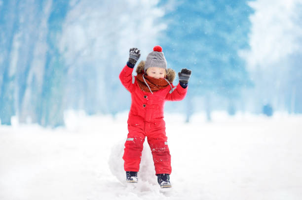 istock Little boy in red winter clothes having fun with snowball 885023054