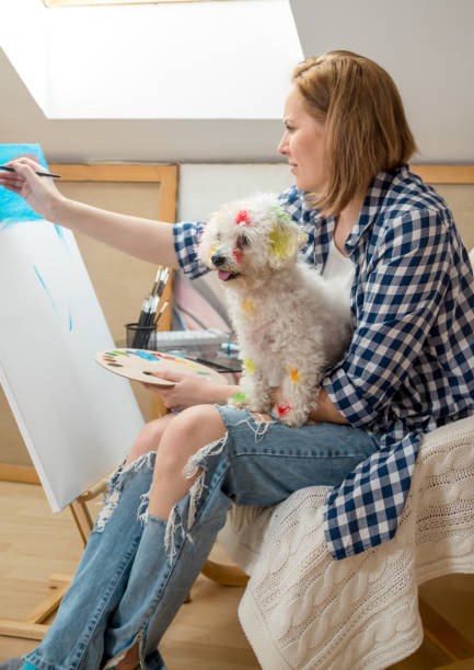 istock Happy young woman paints on canvas 885027050