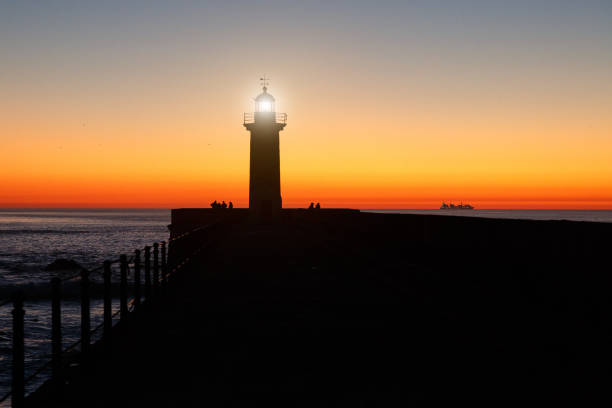 istock lighthouse on the ocean, silhouette at sunset. 885027574