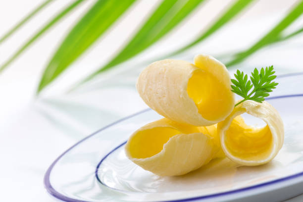 istock three Butter curl or roll, on plate front view.greenery in the background 885030204