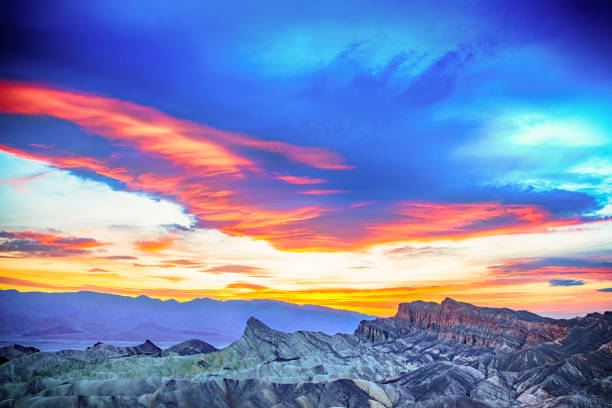 The sun setting beyond the mountains from the badlands of Zabriskie Point located within Death Valley National Park.