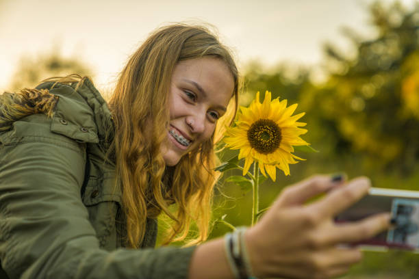 istock A young woman makes a fun selfie with a sunflower 885048852