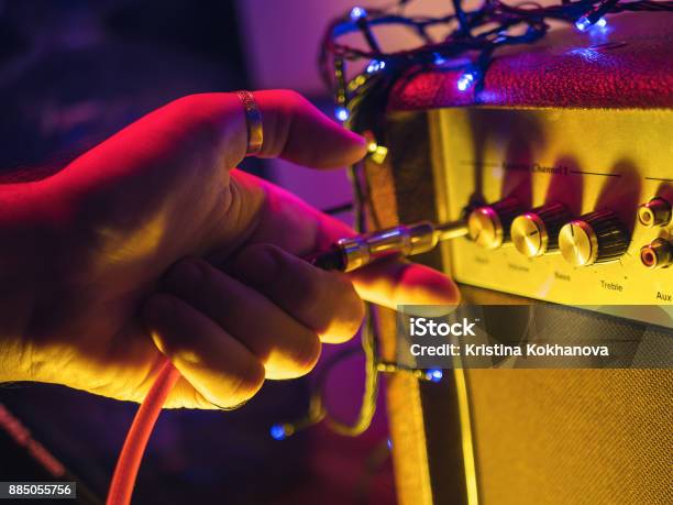 Man Plugging Jack Into The Guitar Amplifier Closeup For Music Entertainment Themes Neon Colorful Light Stock Photo - Download Image Now