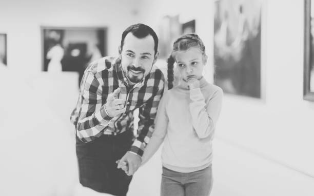 istock satisfied father and daughter regarding paintings in museum 885075496