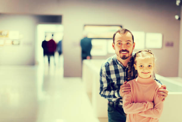 istock Man and small daughter looking paintings in museum 885075520