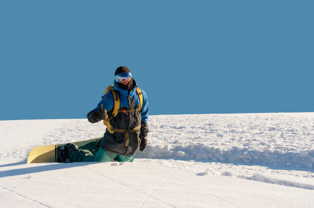 istock Smiling man snowboarder resting kneeling and showing thumbs up 885102538