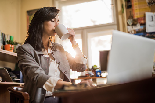 Young occupied woman drinking coffee.