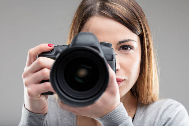 写真を撮るデジタル一眼レフを持つ女性 - コンテスト ストックフォトと画像