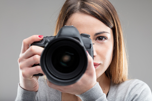 woman with a DSLR camera (blurred) with her intense look in focus - photographer concept