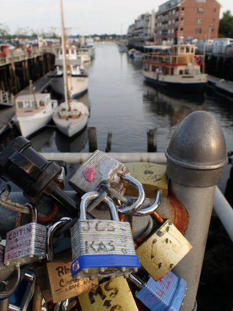 A multitude of love padlocks (token locks set by couples to signify their union, their respective keys hidden or discarded) shackled onto the railings and balustrades of a bridge overlooking the marina in Portland, Maine (Aug 2015)