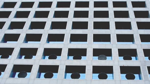 istock Gray stone modern facade of a building with windows reflecting the sky.abstract building 885206648