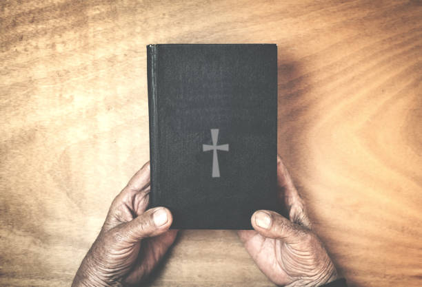 istock Old hands with a bible on a wood background. 885209808