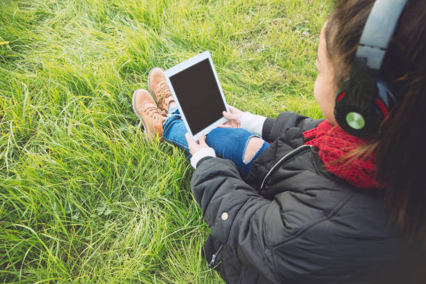 istock young woman holding tablet PC with black screen on lawn 885212624