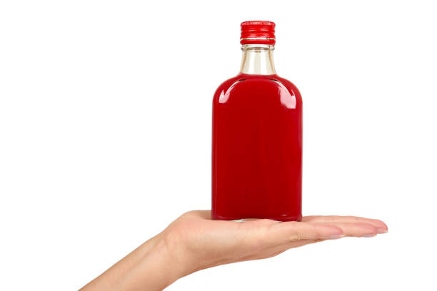 glasflasche mit roten tinktur in der hand isolierten auf weißen hintergrund. alkoholproblem - alcoholism narcotic excess alcohol stock-fotos und bilder