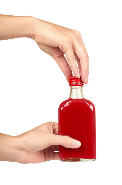 glass bottle with red tincture in hand isolated on white background. alcohol problem - alcoholism narcotic excess alcohol imagens e fotografias de stock