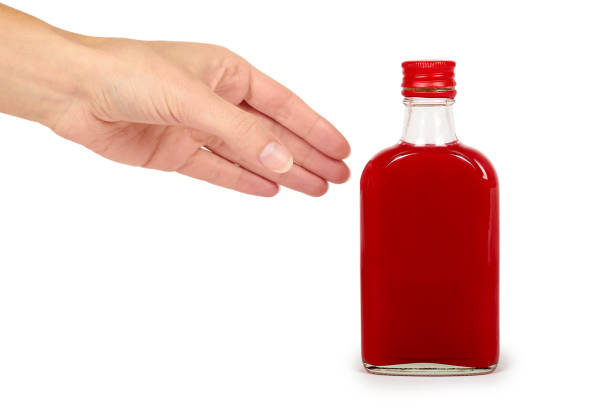 glass bottle with red tincture in hand isolated on white background. alcohol problem - alcoholism narcotic excess alcohol imagens e fotografias de stock