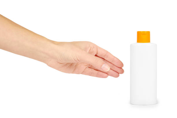 istock Plastic white shampoo bottle with orange cap in hand isolated on white background. Gel dispenser for hair care. Container with body lotion. 885232000
