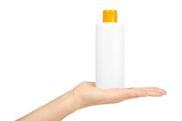 istock Plastic white shampoo bottle with orange cap in hand isolated on white background. Gel dispenser for hair care. Container with body lotion. 885232004