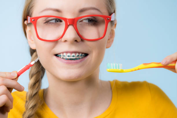 istock Woman smiling cleaning teeth with braces 885281196