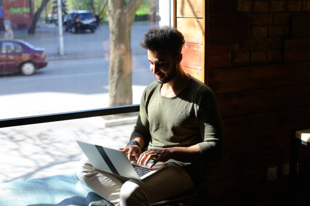 istock Man sits in new apartment and uses laptop 885311572
