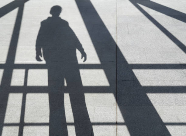 istock shadow of a man on the sidewalk among the beams 885329162