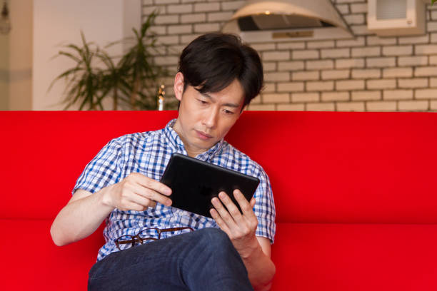 istock Japanese young man watching the internet contents with tablet device 885338154