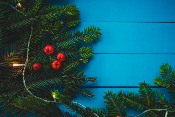 istock Evergreen branch with red berries on blue boards 885351278