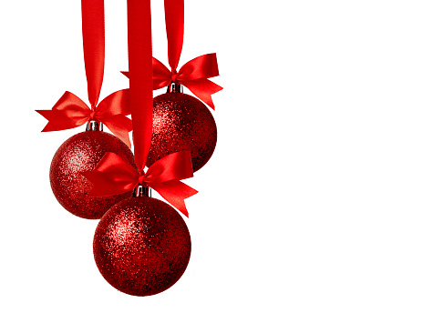 Close up of red and golden colored christmas baubles with christmas lights in the background.